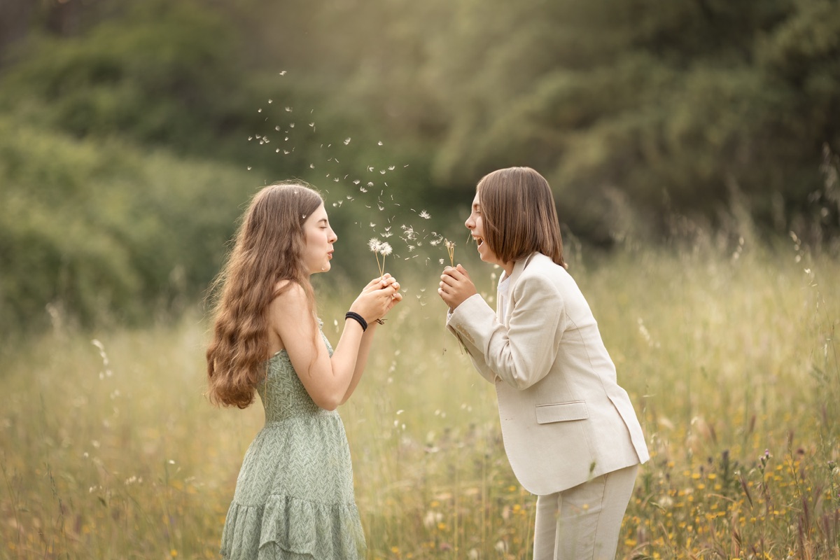 Dos niñas comparten un momento con flores en una sesión de exterior.