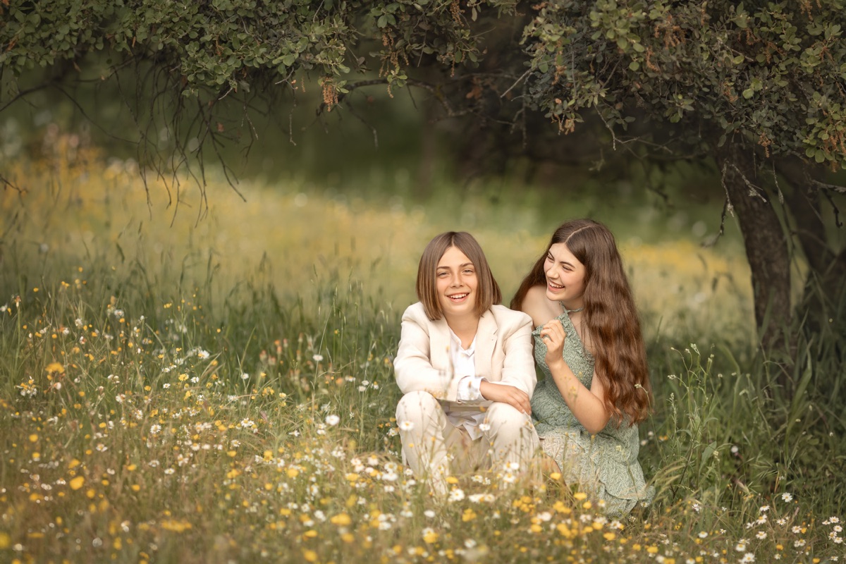 Dos hermanas posan juntas en un campo durante una sesión de Comunión.