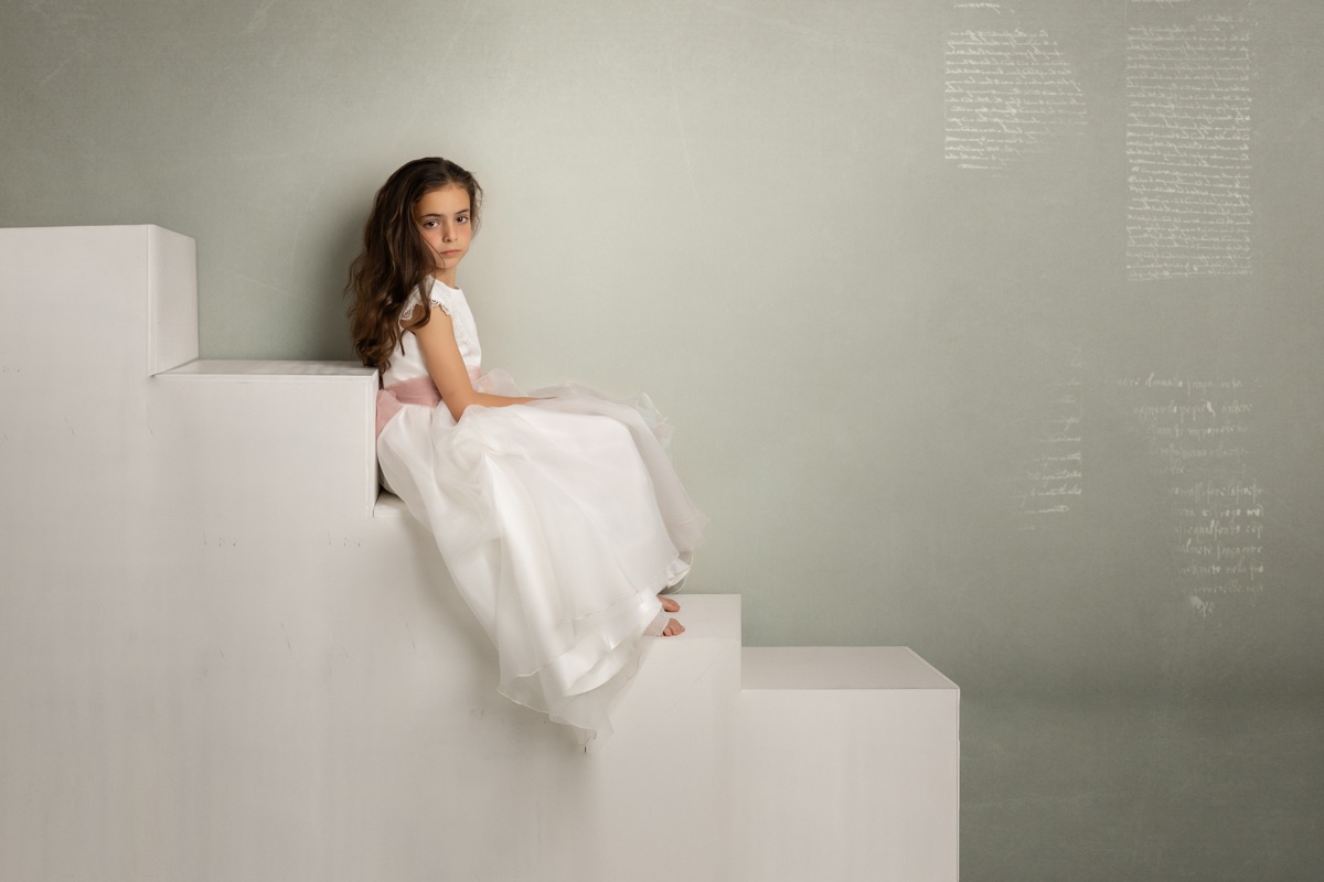 Retrato Fine Art de una niña de Comunión sentada en una escenografía geométrica.