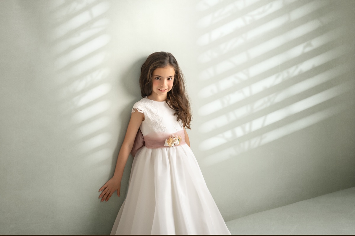 Retrato de una niña de Comunión con luz y sombras de ventana.