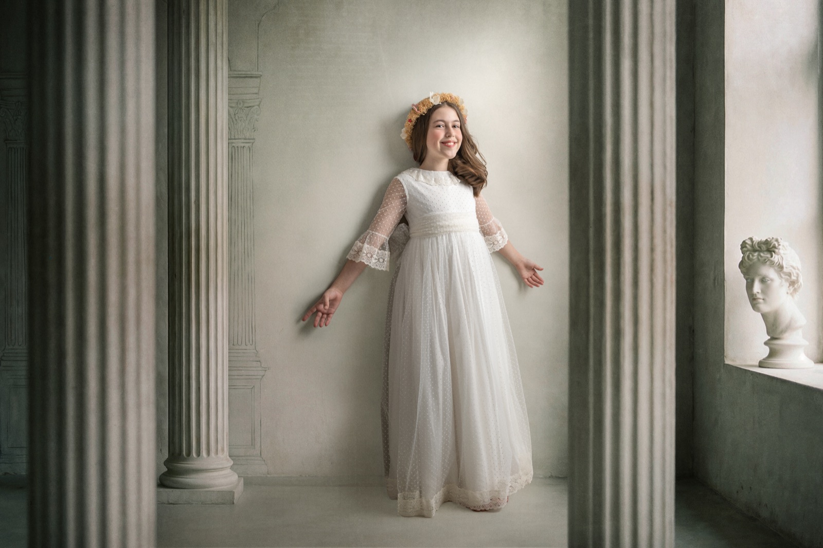 Niña con vestido blanco de Comunión entre columnas clásicas en un retrato Fine Art.
