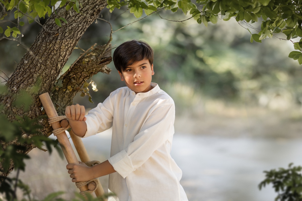 Retrato de un niño con traje de Comunión en un campo.