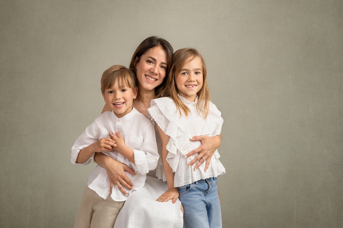 Una madre rodea con sus brazos a sus dos hijos en un retrato luminoso
