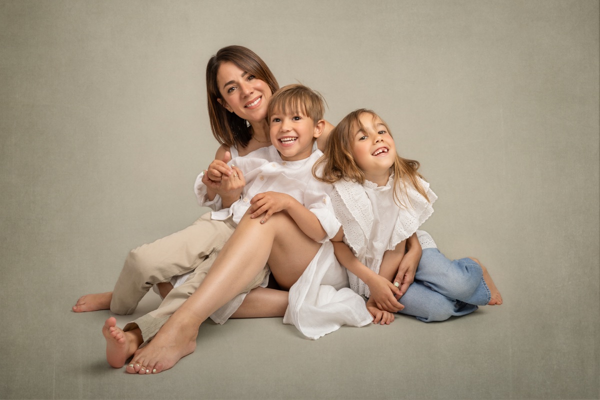 Una madre y sus dos hijas se ríen sentadas juntas en el estudio