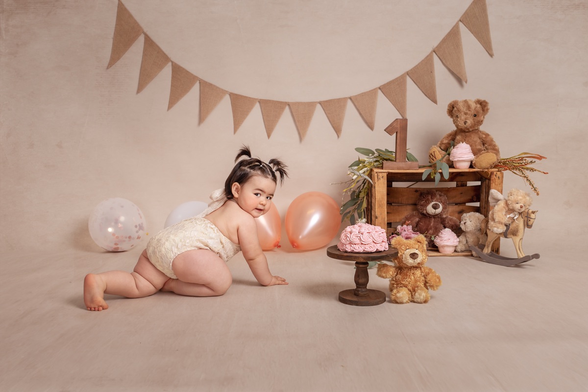 Bebé gateando en un escenario decorado para su primer cumpleaños