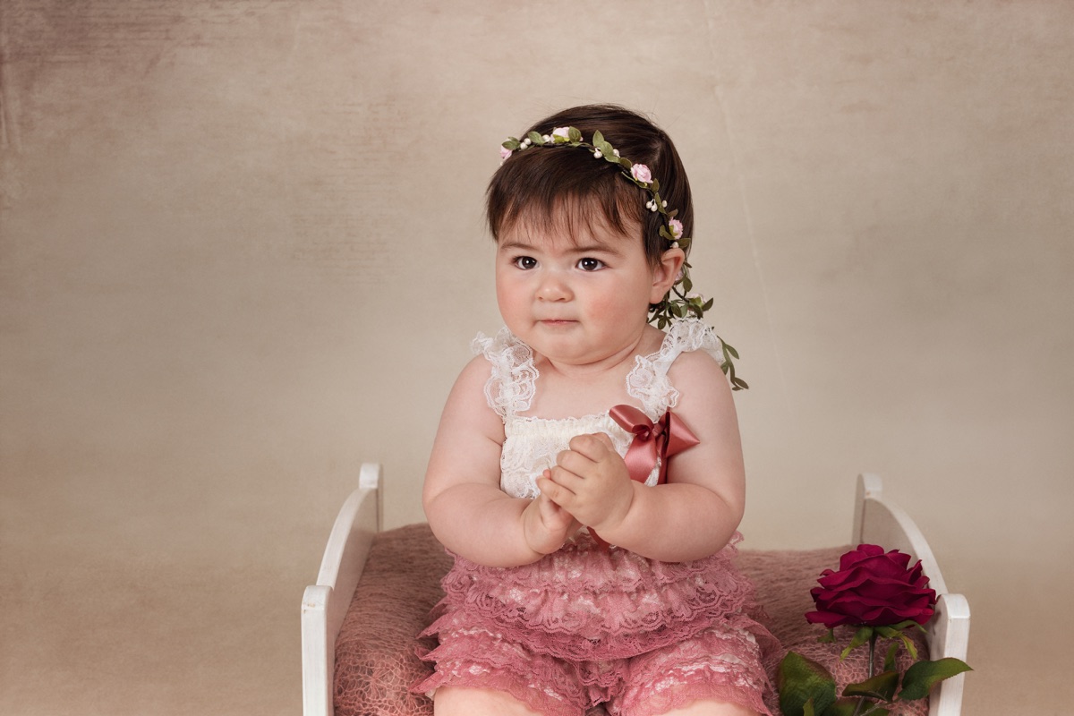 Niña sentada con vestido rosa durante una sesión de fotografía infantil