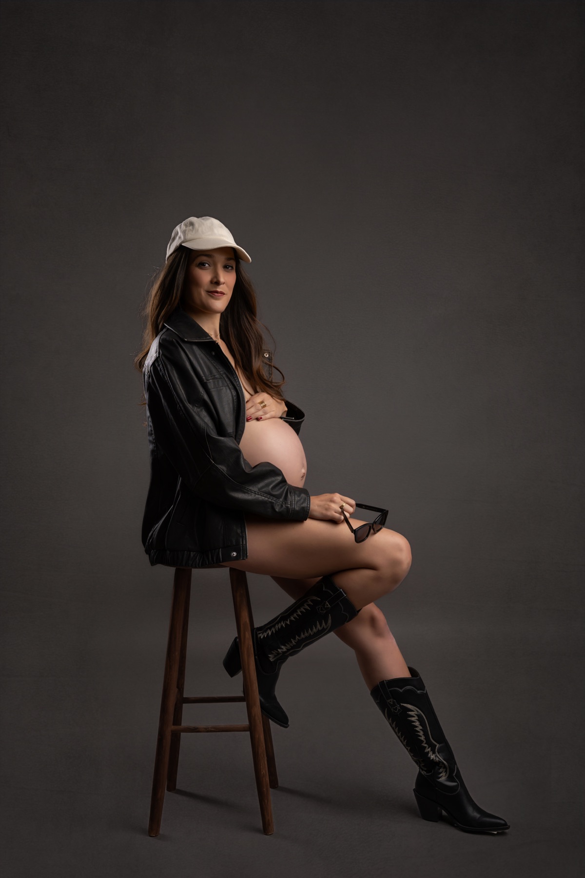 Retrato de embarazo en estudio con chaqueta negra y sombrero