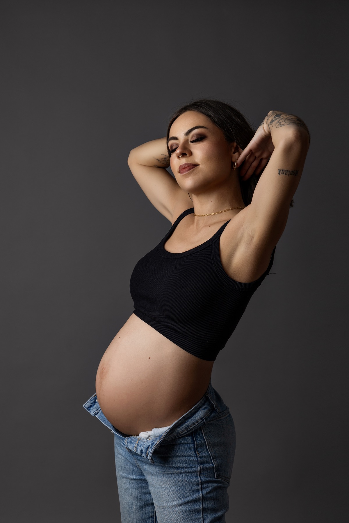 Retrato de maternidad en estudio con vestido claro y sombrero de ala ancha