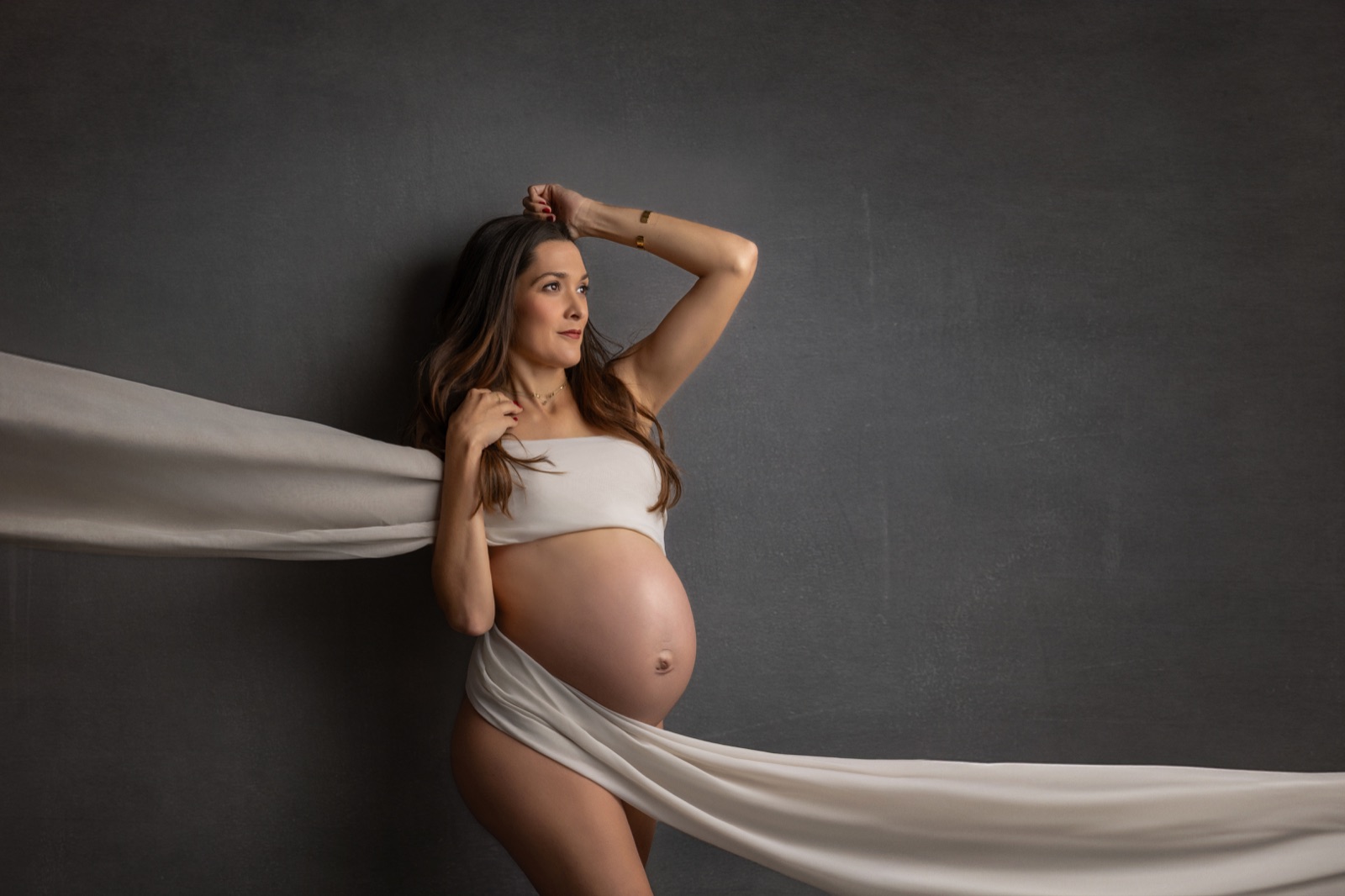 Retrato de maternidad en estudio, con una futura mamá en una composición artística de tonos oscuros, en Villanueva de la Cañada