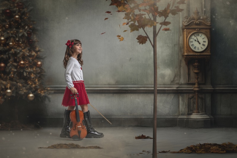 Niña con un violín junto a un reloj antiguo en una escena navideña