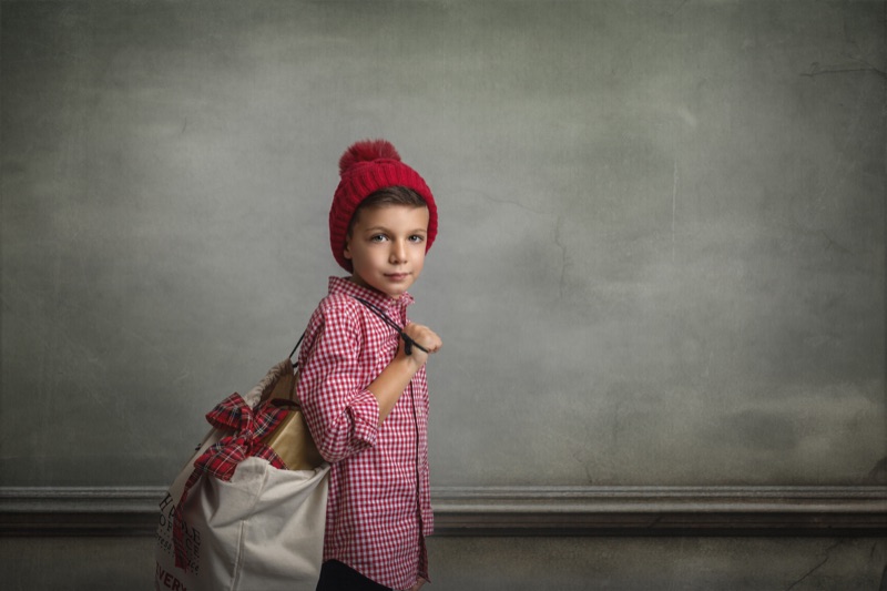 Retrato de una niña con gorro rojo y una bolsa de viaje