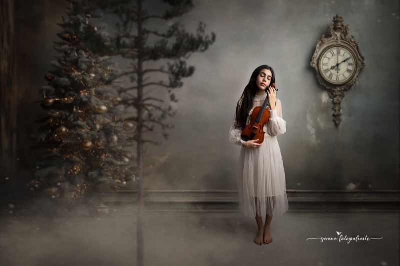 Retrato infantil con violín en un escenario navideño