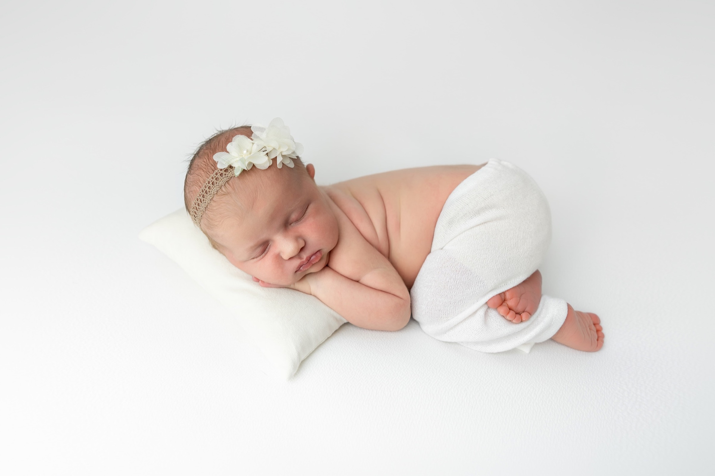 Bebé recién nacida dormida en una pose natural durante una sesión de fotografía newborn en estudio