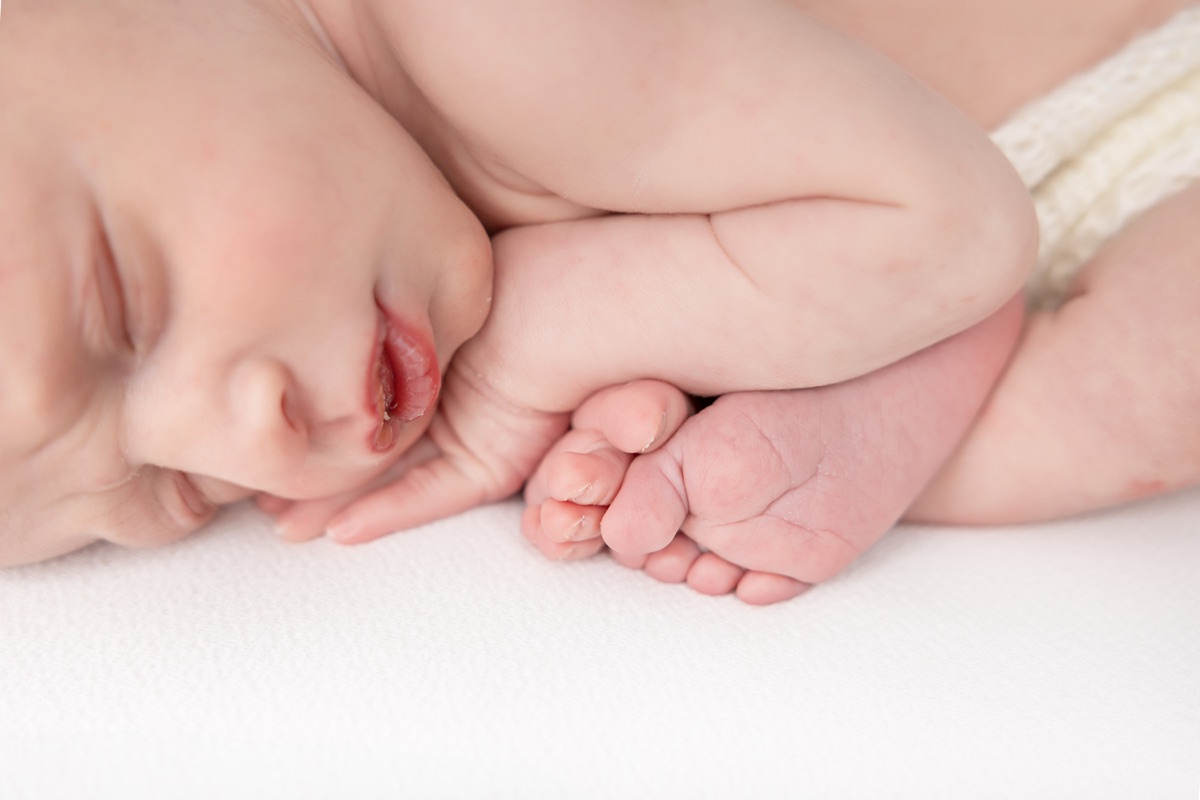 Detalle de las manos y el rostro de un bebé recién nacido dormido durante una sesión newborn en Villanueva de la Cañada