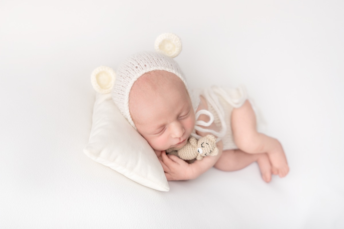 Bebé recién nacido dormido con gorrito blanco de orejitas durante una sesión newborn en Villanueva de la Cañada