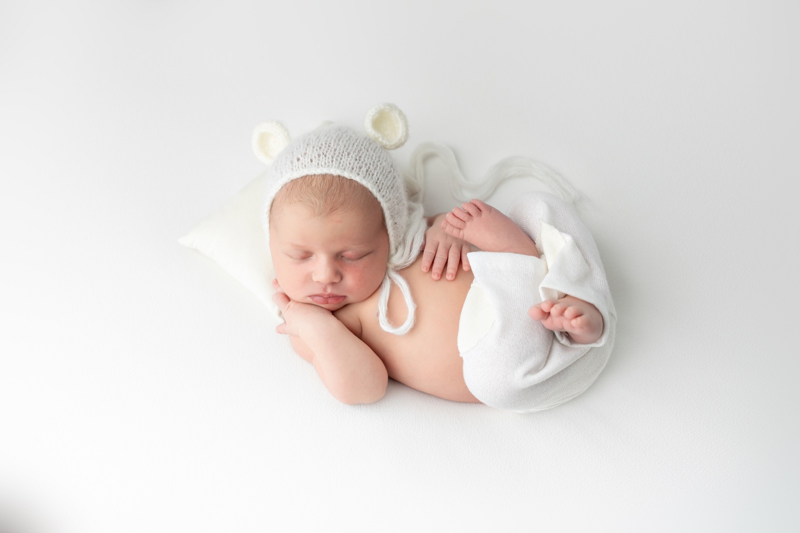 Bebé recién nacido dormido con gorrito de punto claro durante una sesión newborn en Villanueva de la Cañada