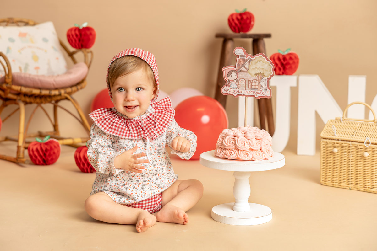 Bebé jugando con una fresa de atrezo en una sesión Smash Cake.