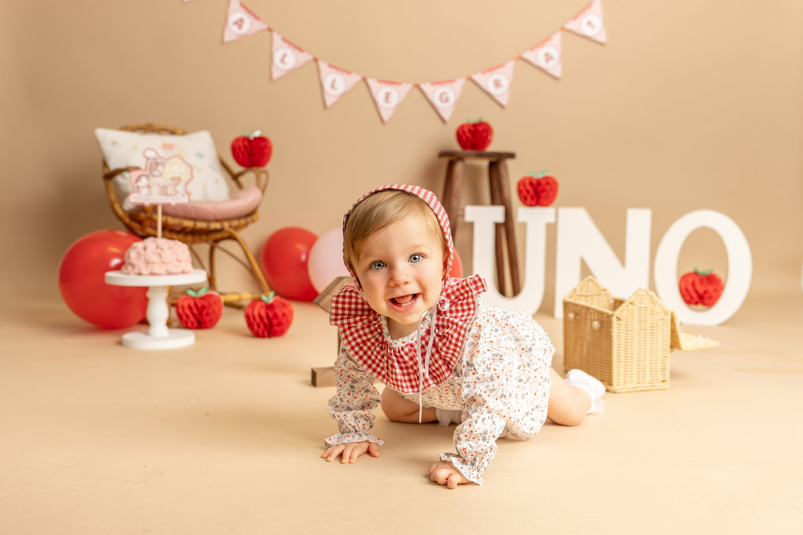 Bebé sonriente en una sesión Smash Cake con decorado de fresas y atrezo.