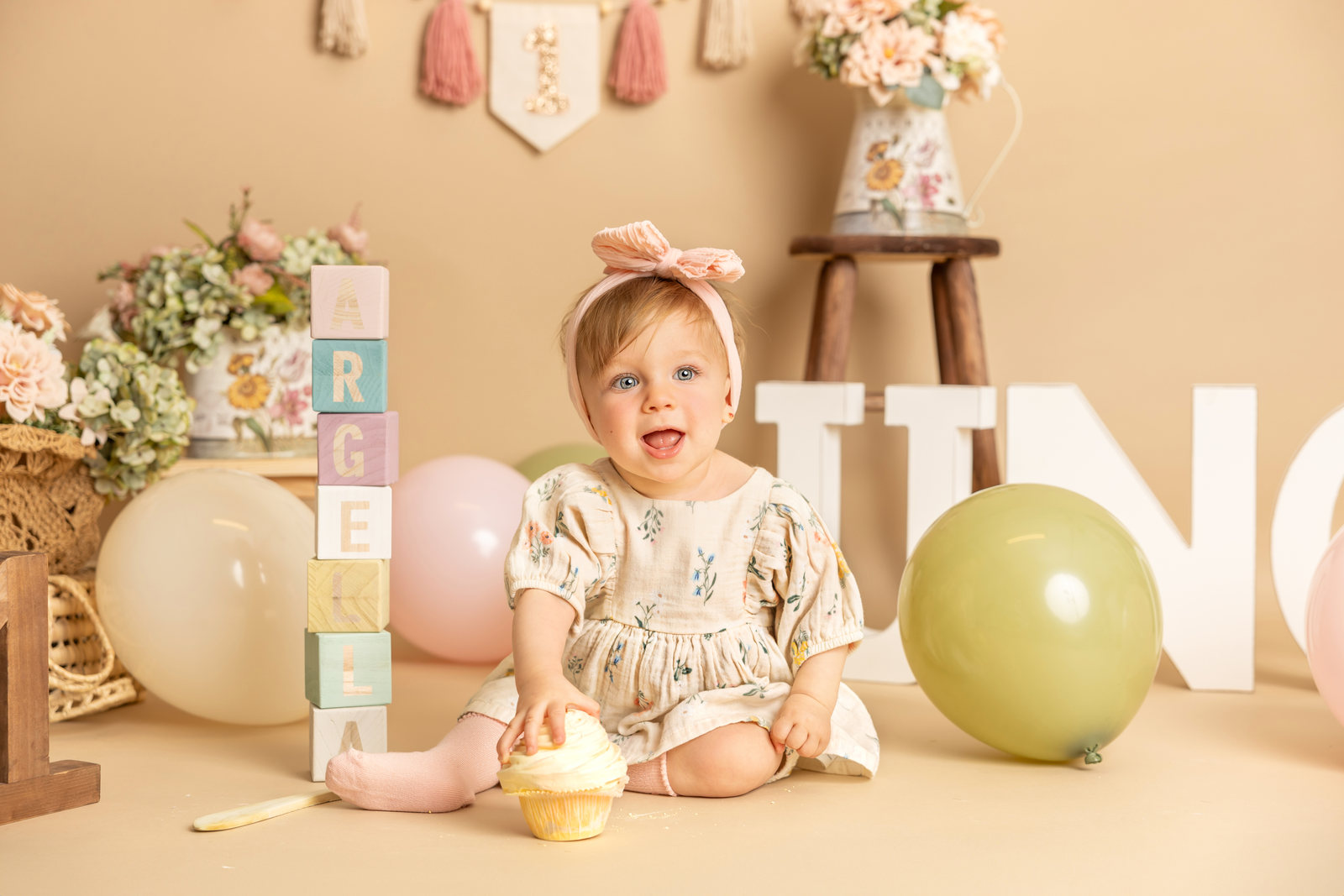 Bebé con vestido claro en un decorado pastel de cumpleaños Smash Cake.