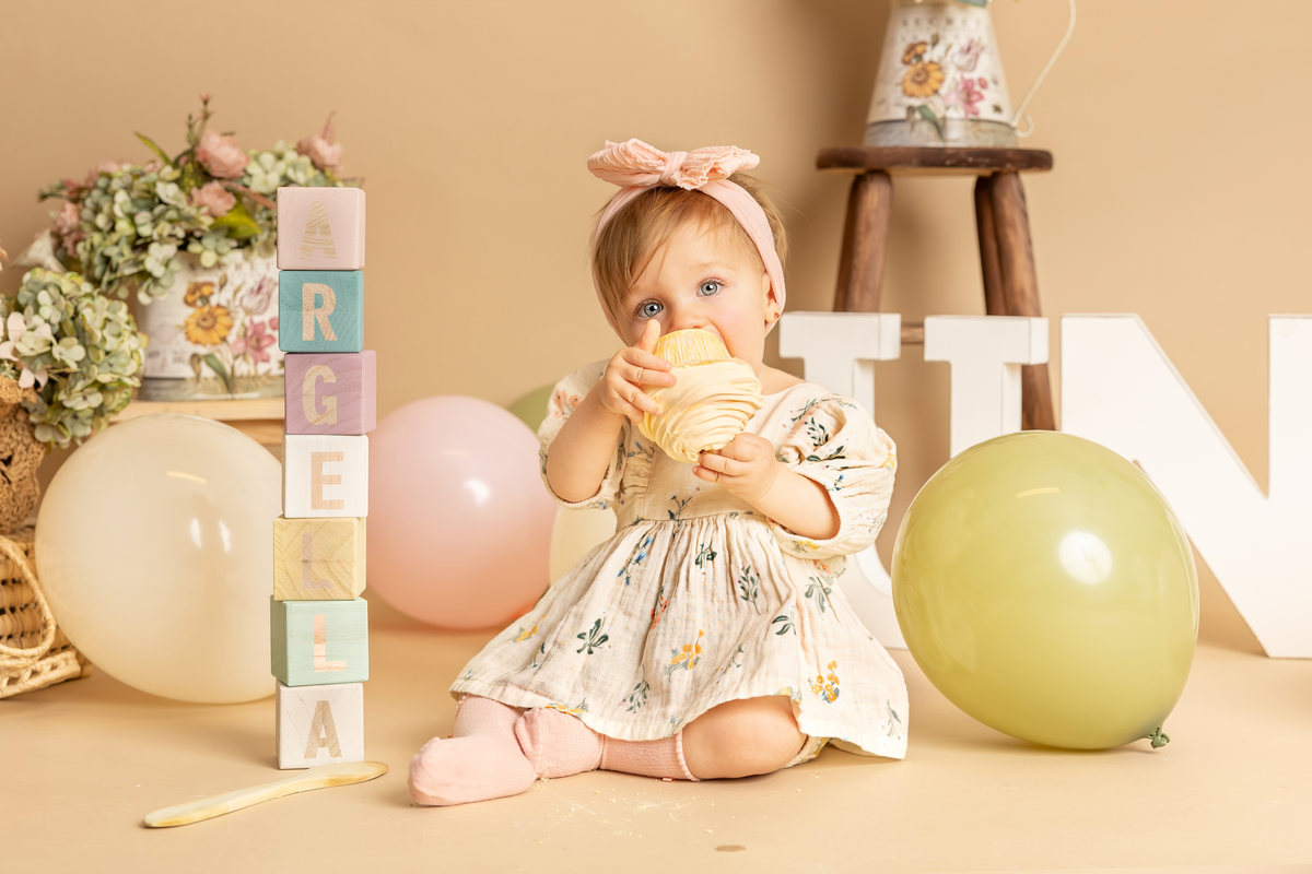 Bebé explorando un elemento de atrezo en su sesión de primer cumpleaños.