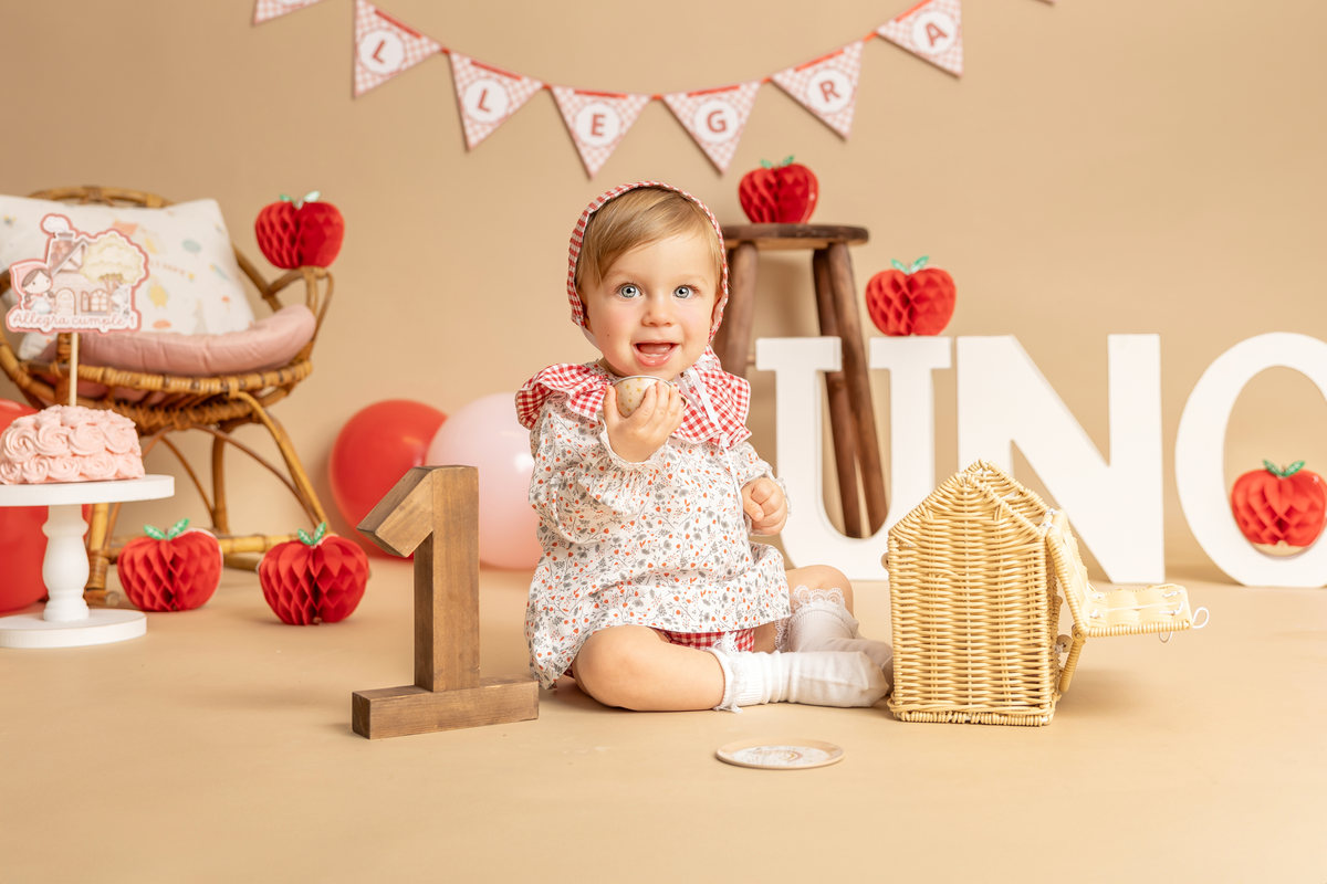 Bebé sentada y sonriente junto a un pequeño decorado Smash Cake.