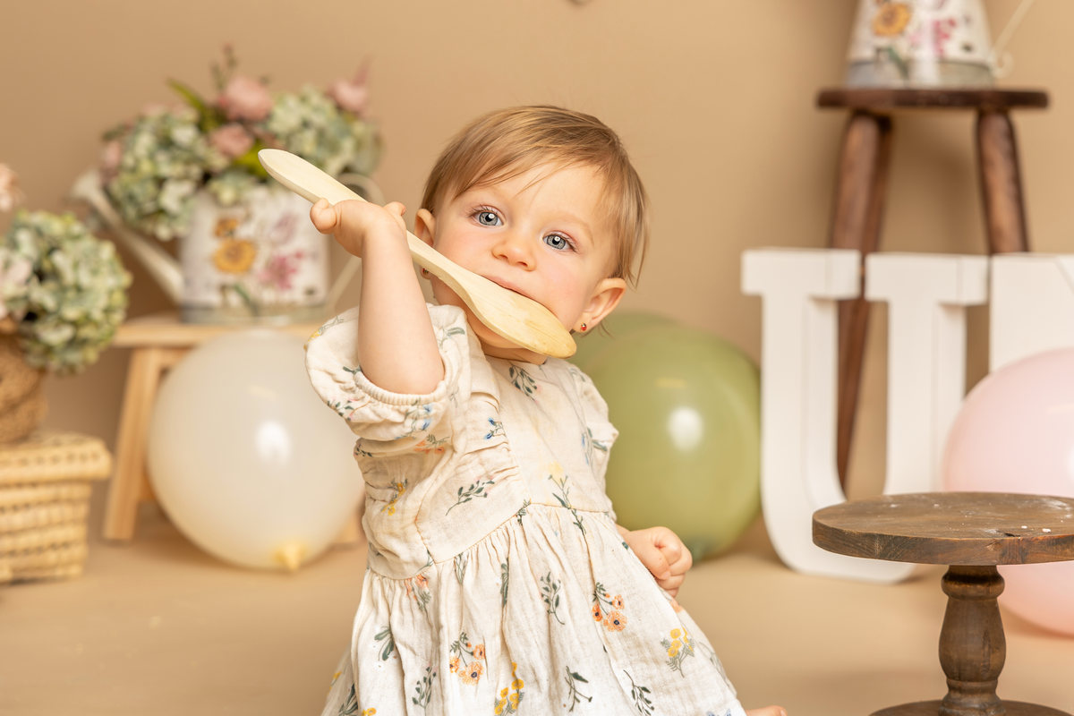 Retrato cercano de bebé jugando con un globo en su sesión Smash Cake.