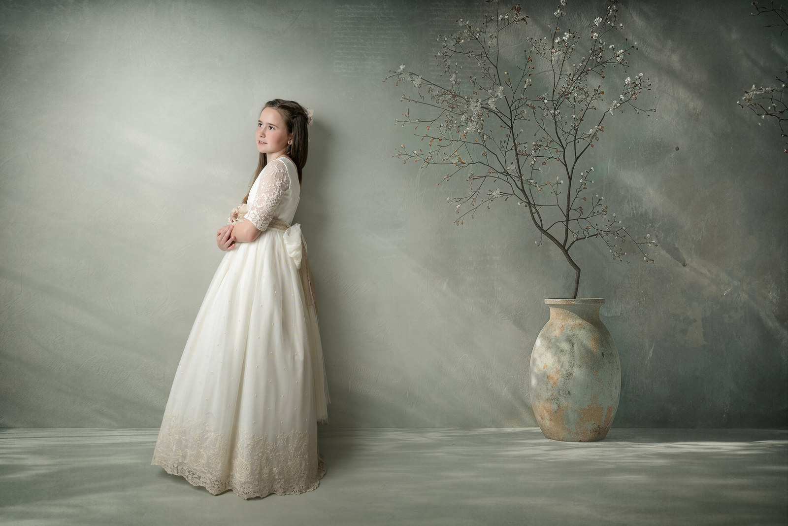 Niña con vestido de comunión en un decorado artístico de estudio